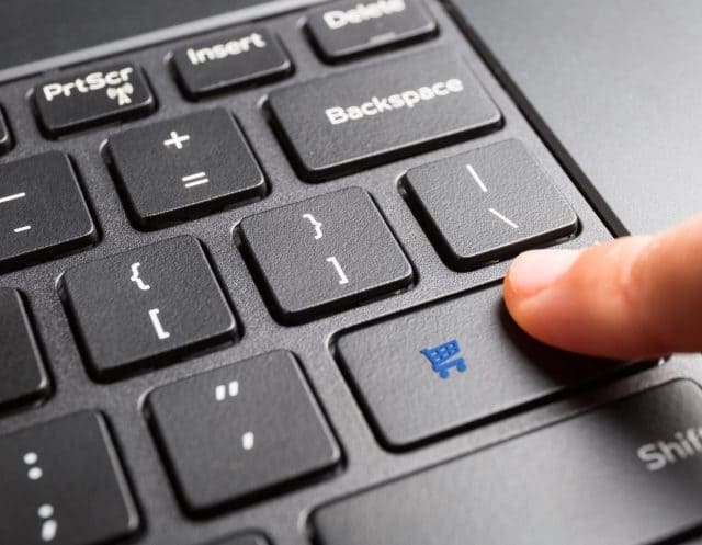 laptop keyboard with finger pressing shopping cart key, online shopping concept